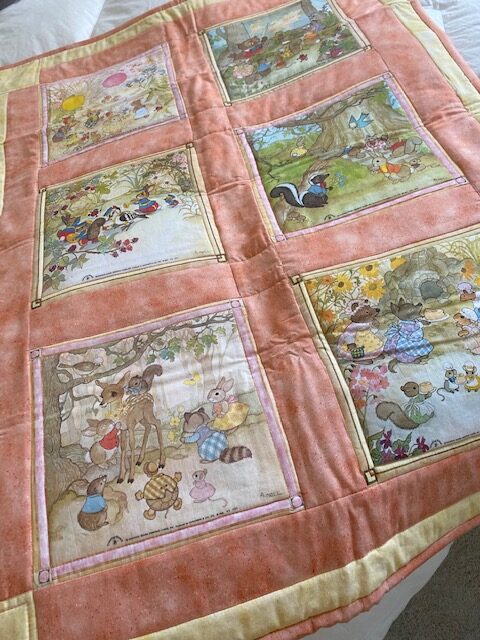 machine-quilted baby quilt with woodland creature scenes