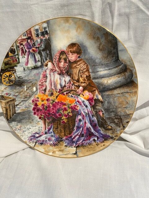 front of a collector plate - showing a boy and a girl with a basket of flowers, seat next to a column, in an urban scene with a flower seller negotiating a sale with gentlemen in the background