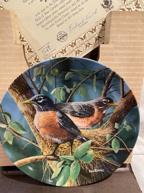 front of a collector plate - showing two American robins building a nest